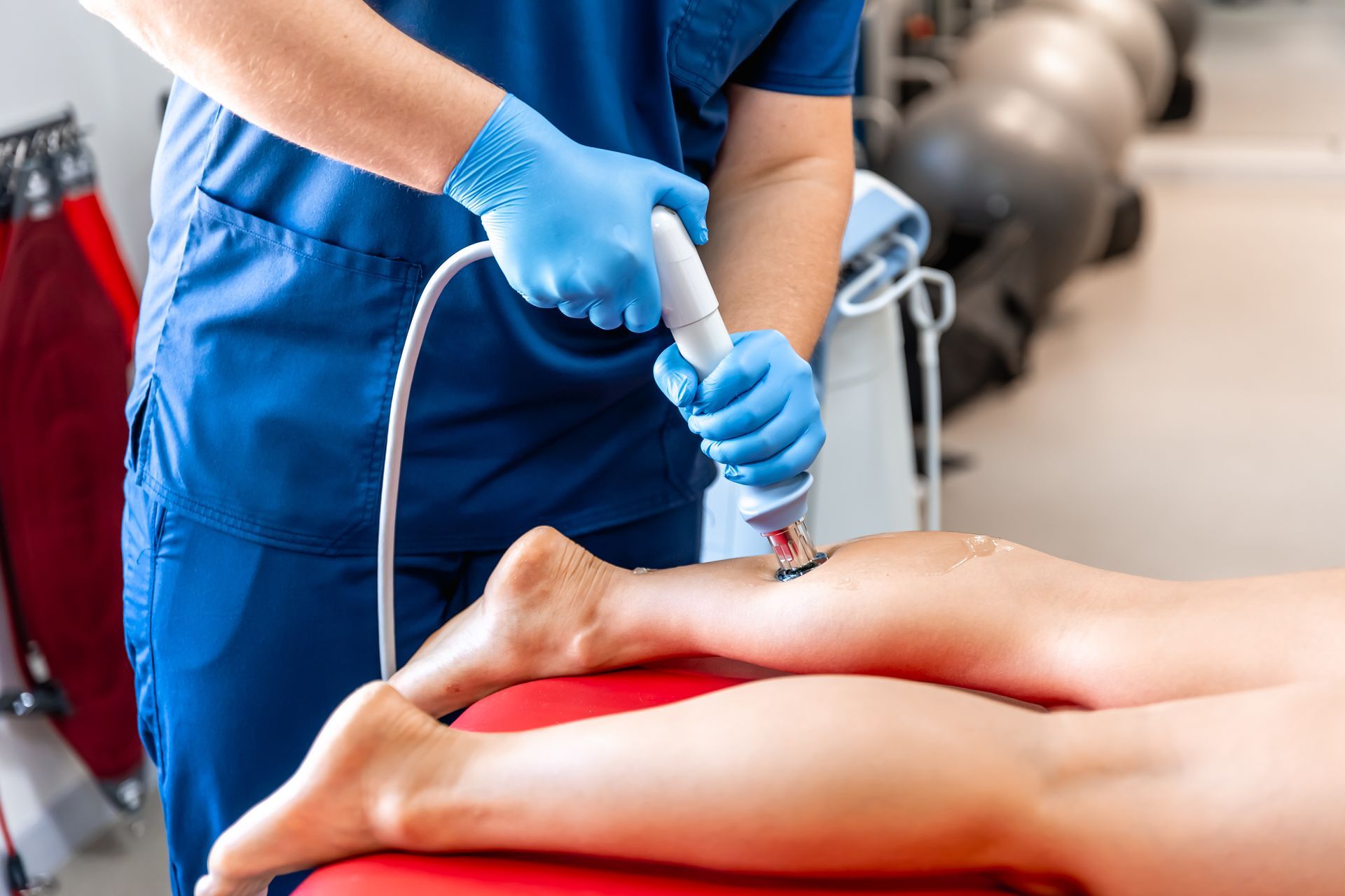 Medical professional performing ultrasound therapy on a patient's leg.