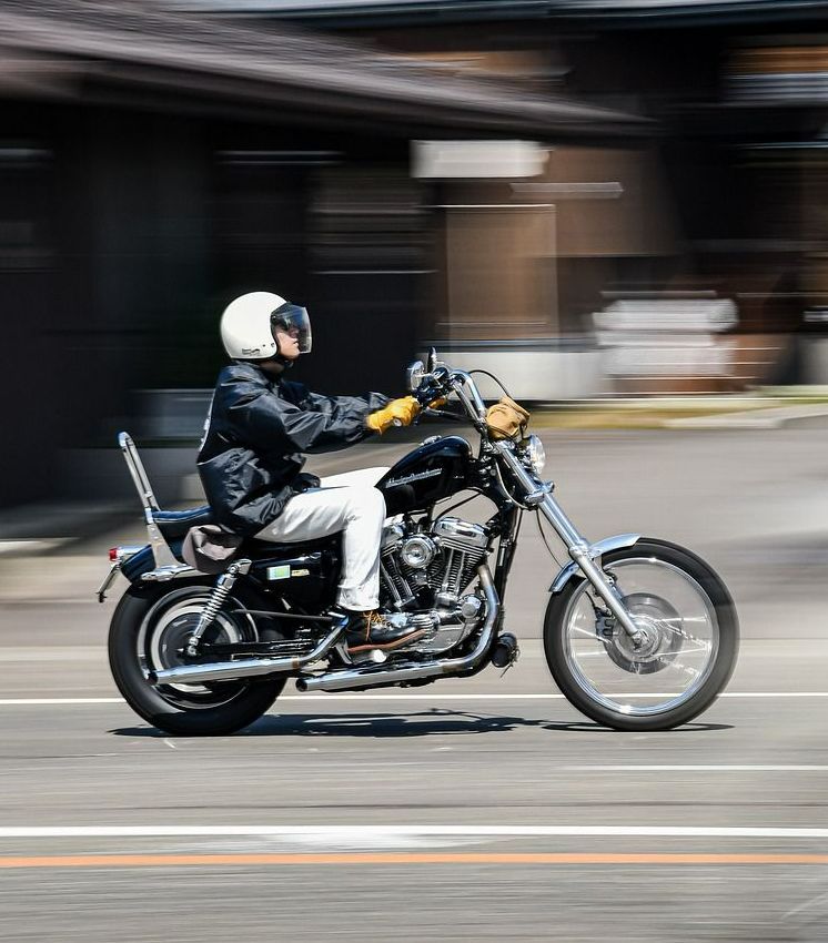 A man is riding a motorcycle down a street.