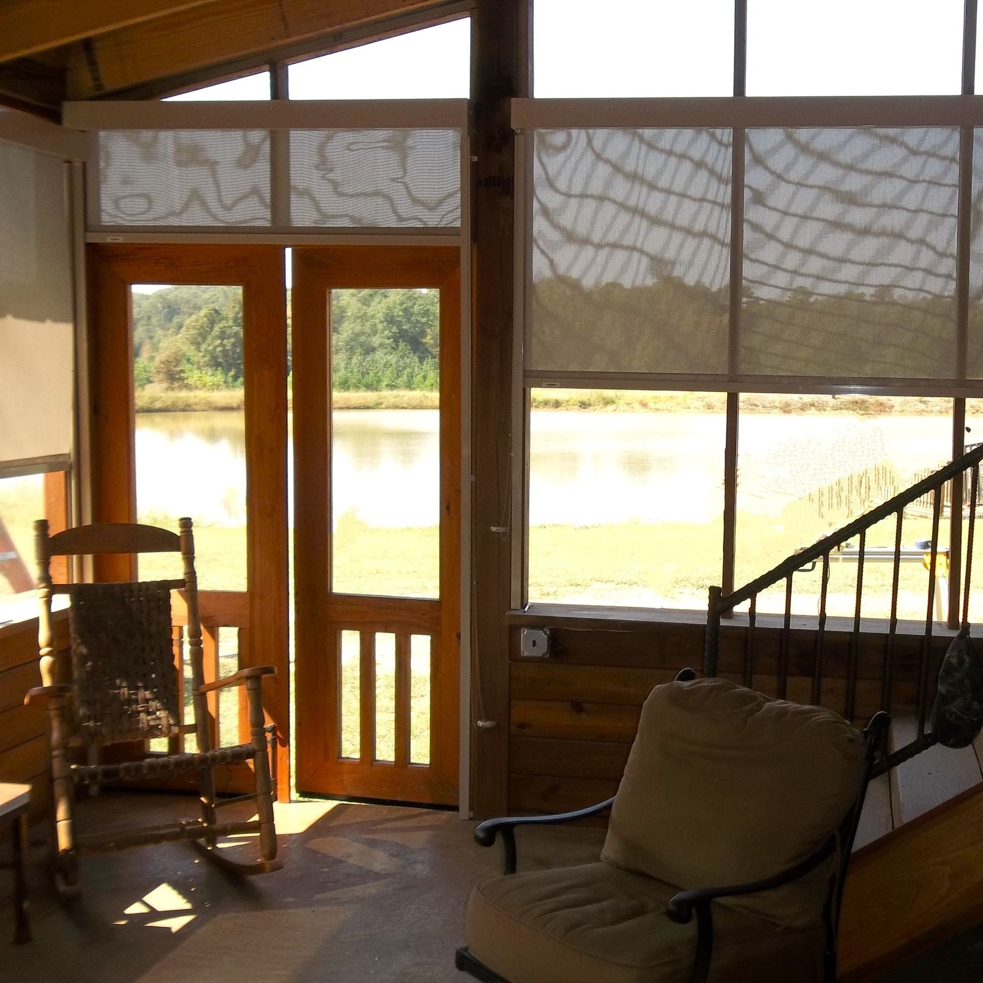 a screened in porch with a table and bench and a ceiling fan . | Jackson, MS | French Awning an Screen Co