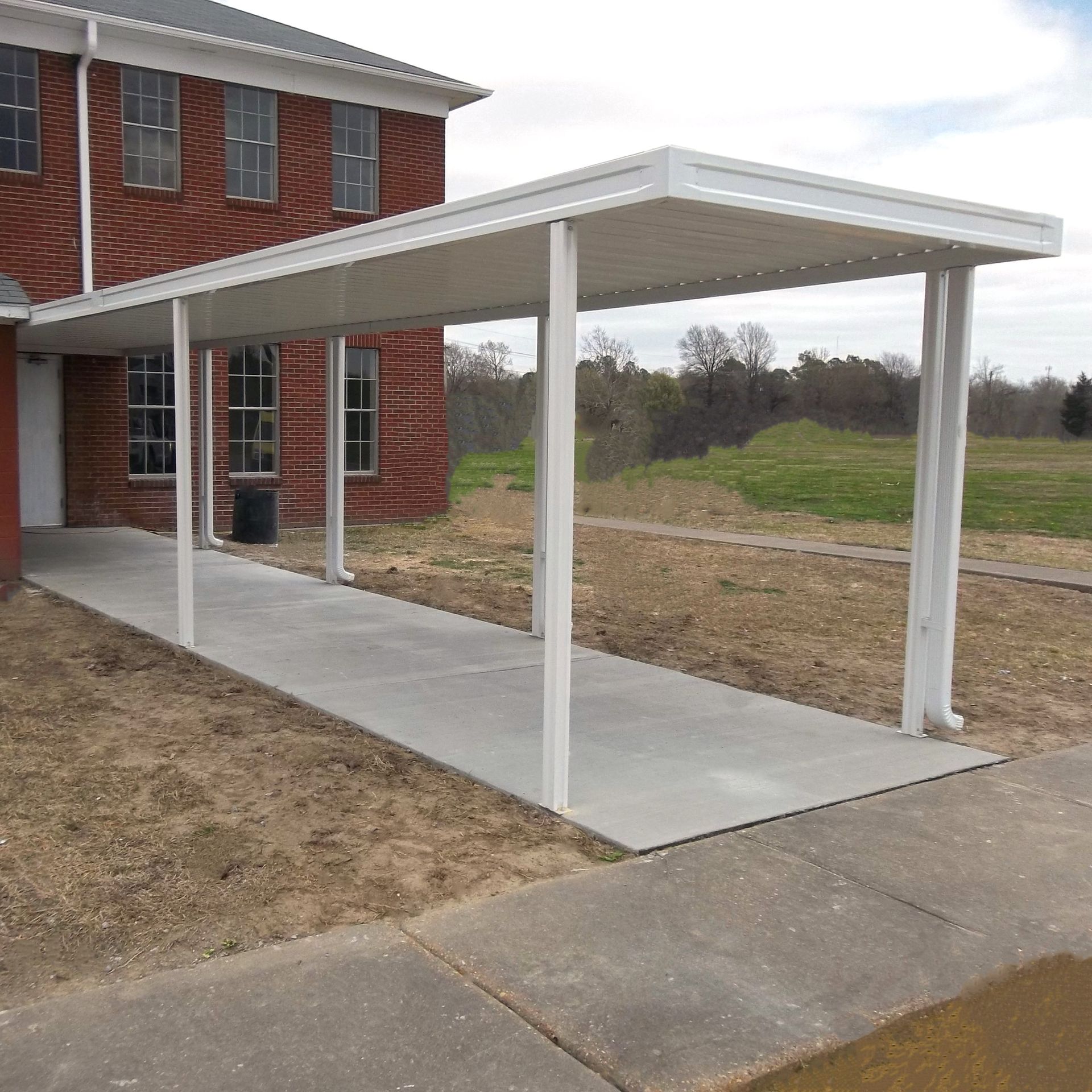 a brick building with a covered walkway in front of it - Road Jackson, MS - French Awning & Screen Co.