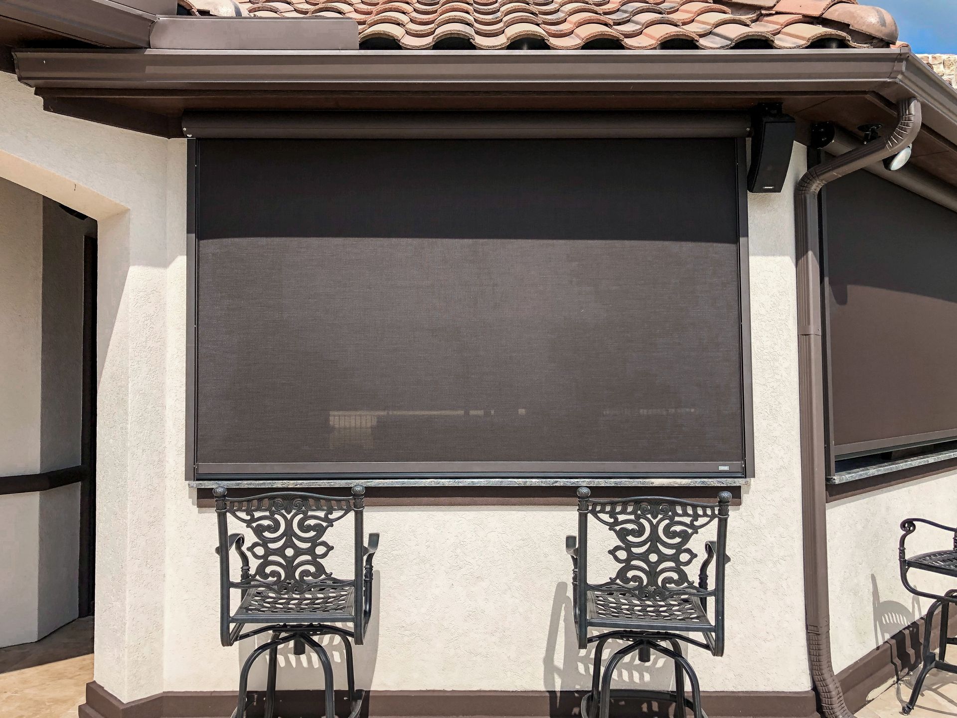 a house with a screened in window and two chairs in front of it .| Jackson, MS | French Awning an Screen Co