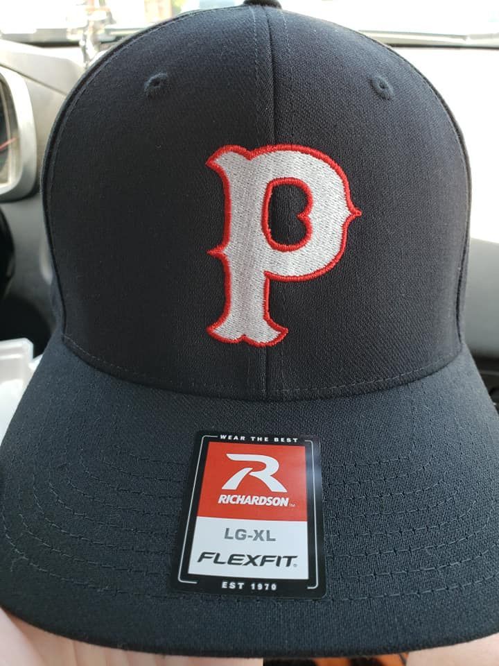 A person is holding a black hat with the letter p on it