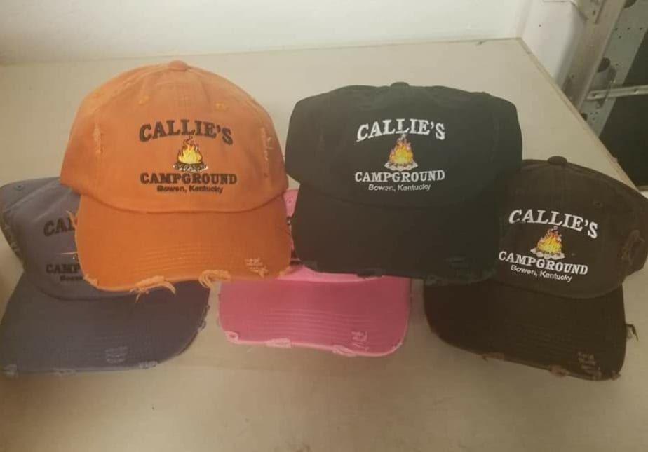 Four callie 's campgrounds hats are sitting on a table.
