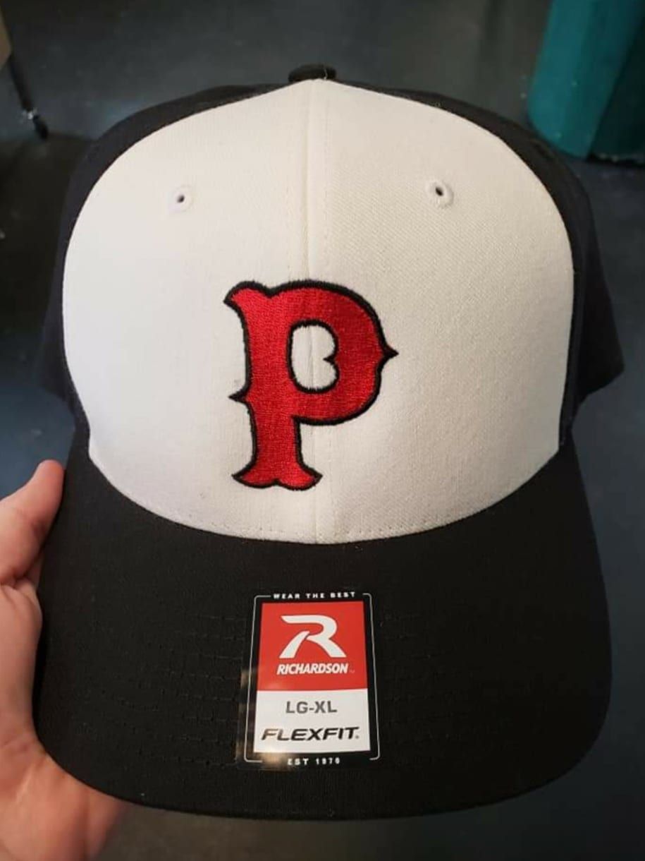 A person is holding a baseball cap with the letter p on it