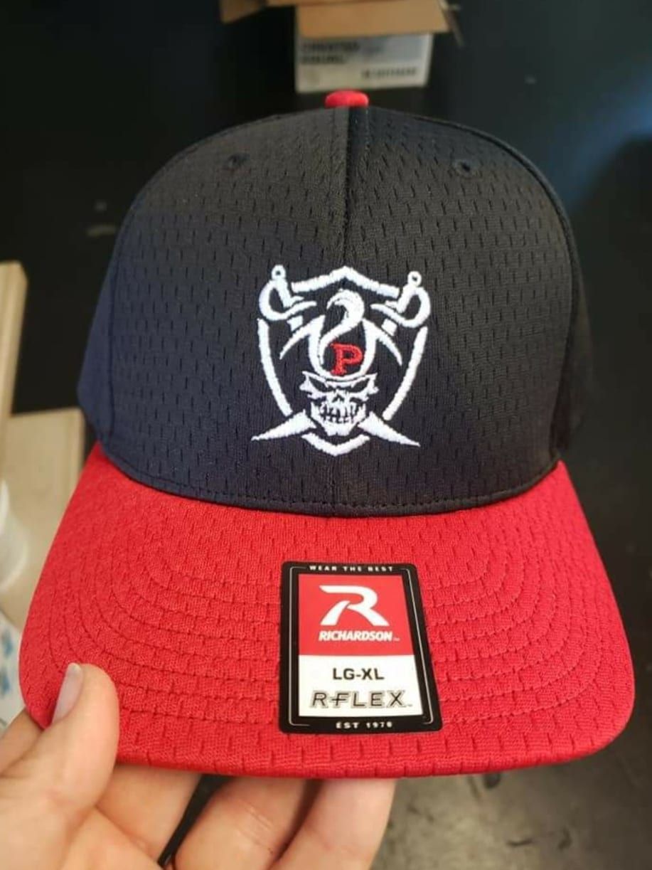 A person is holding a red and black hat with the letter r on it