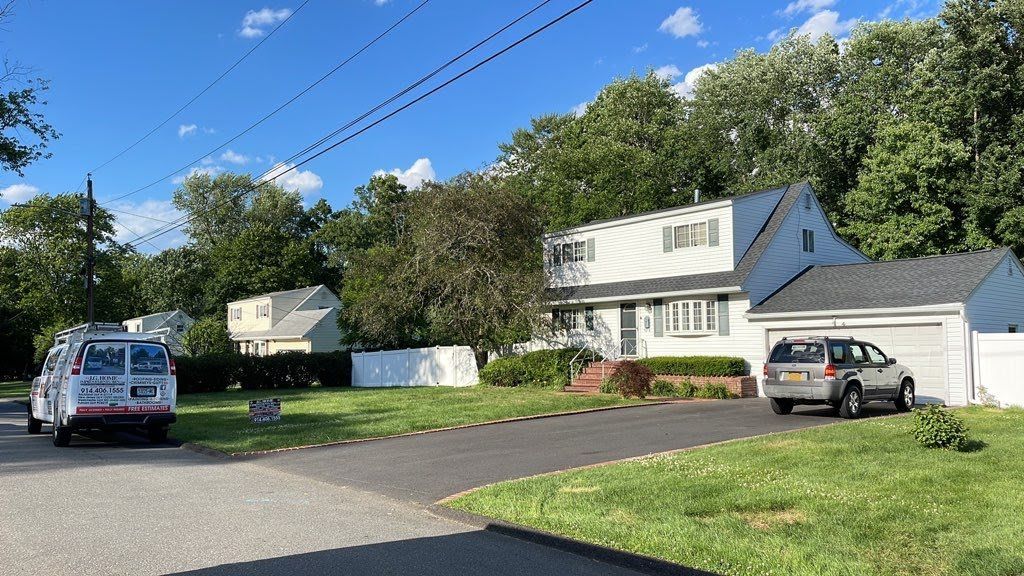 A white van is parked in front of a house.