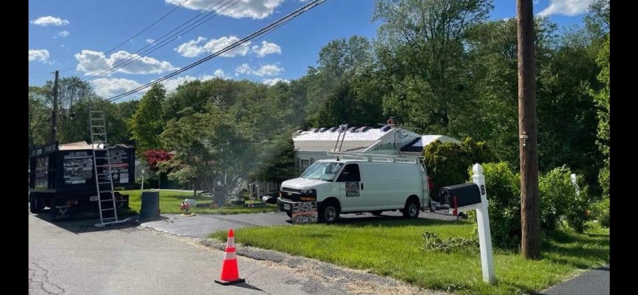 A white van is parked on the side of the road in front of a house.