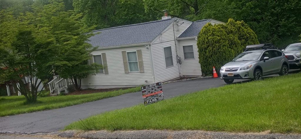 A white house with a car parked in front of it.