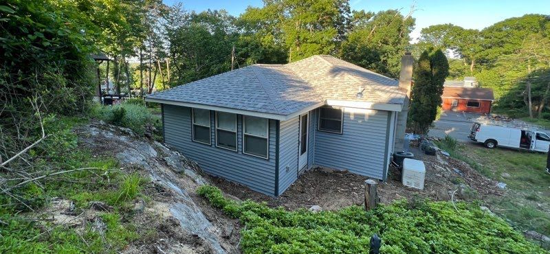 A small house is sitting on top of a hill surrounded by trees.