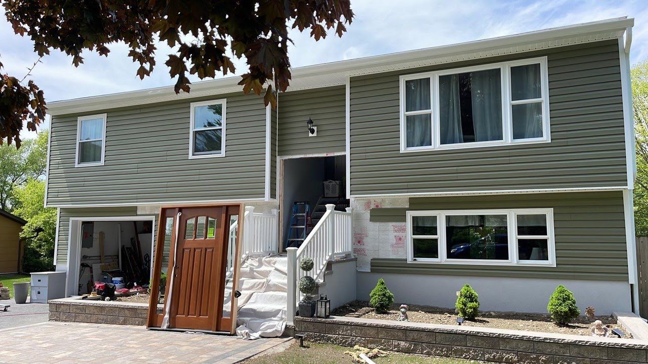 A large house with green siding and white windows