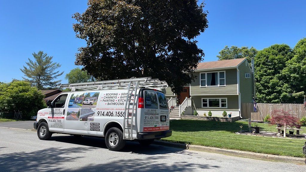 A white van with a ladder on top of it is parked in front of a house.