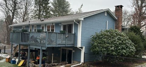A blue house with a large deck and a chimney.