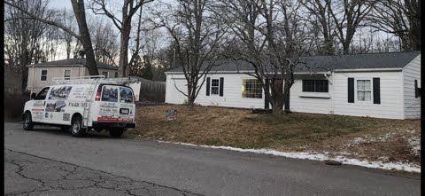 A white van is parked in front of a white house.