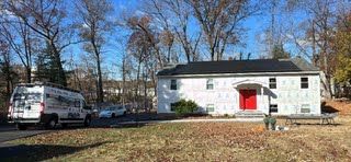 A white house with a red door and a white van parked in front of it.