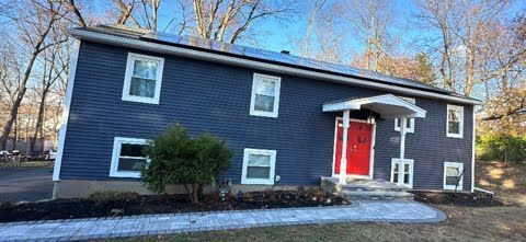 A blue house with a red door and solar panels on the roof.