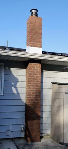 A brick chimney is sitting on the side of a house.