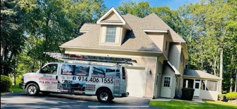 A van is parked in front of a large house.