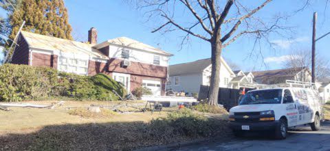 A white van is parked in front of a house.