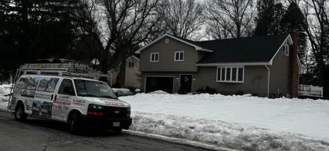 A van is parked in front of a house in the snow.