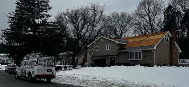 A van is parked in front of a house in the snow.