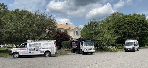 Three vans are parked in a parking lot in front of a house.