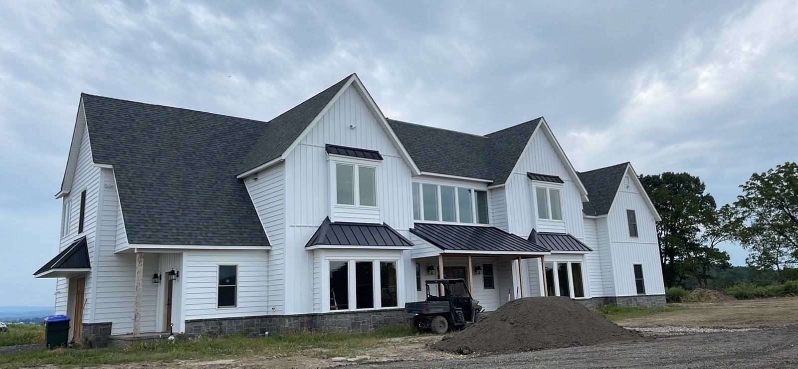 A large white house with a black roof is being built.