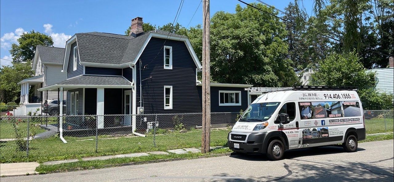 A white van is parked in front of a black house.