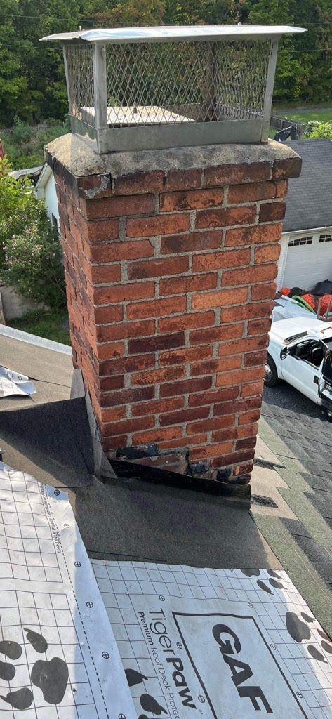 A brick chimney is sitting on top of a roof.