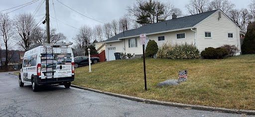 A white van is parked on the side of the road in front of a house.
