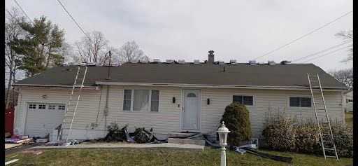 A white house with a roof that is being repaired.