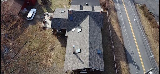 An aerial view of a house with a roof and a road.