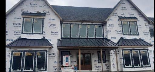 A large house is being built with a metal roof and windows.
