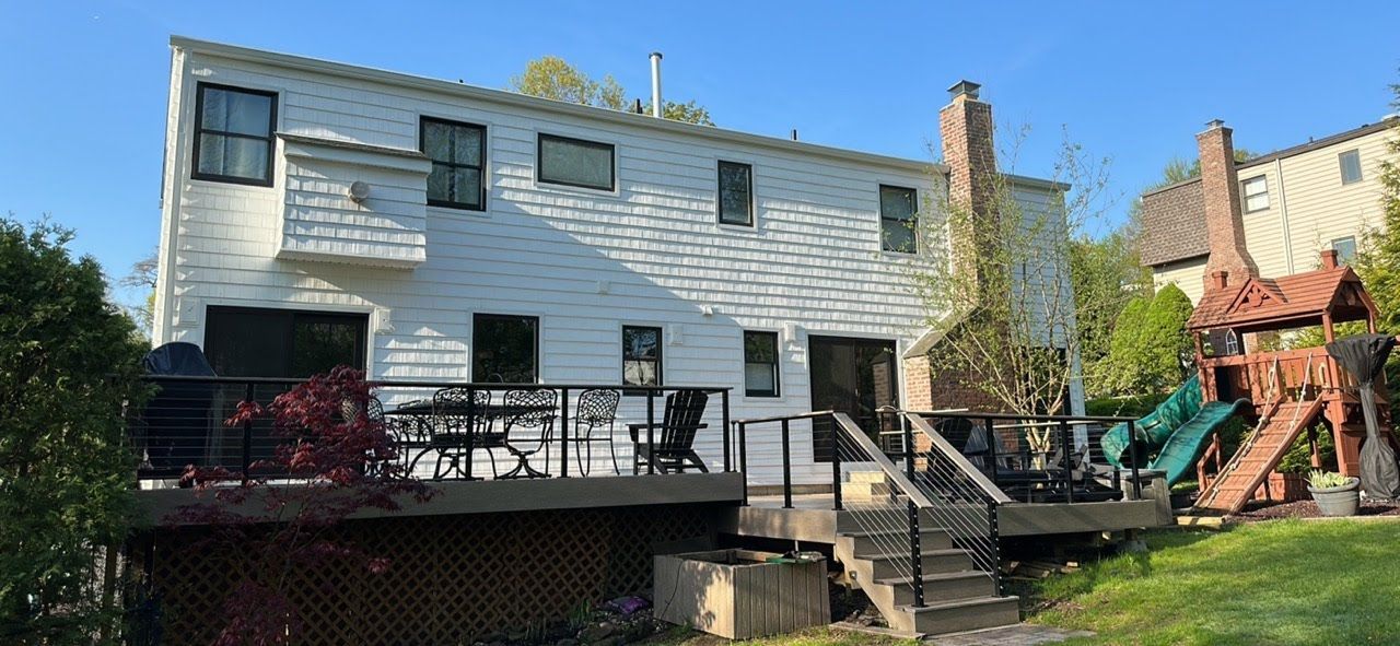 The back of a white house with a deck and a playground.