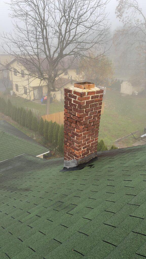 A chimney is sitting on top of a roof in the fog.