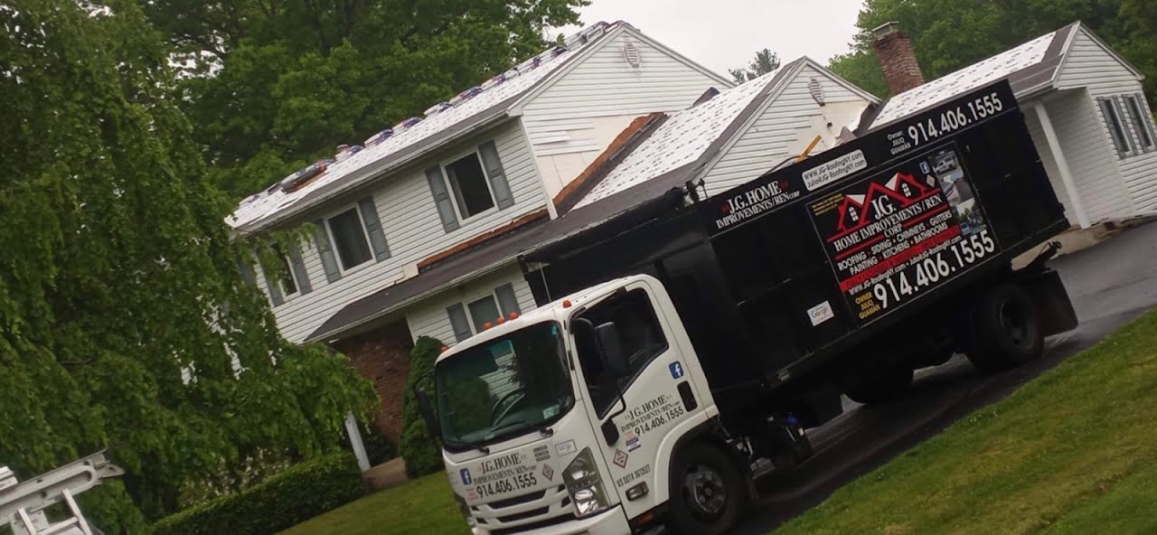 A white truck is parked in front of a white house.