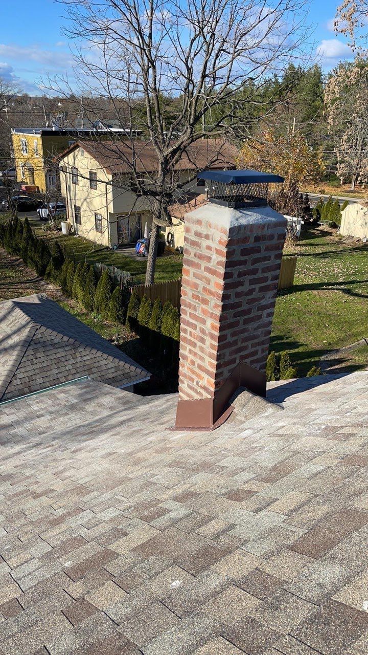 A brick chimney is on the roof of a house.