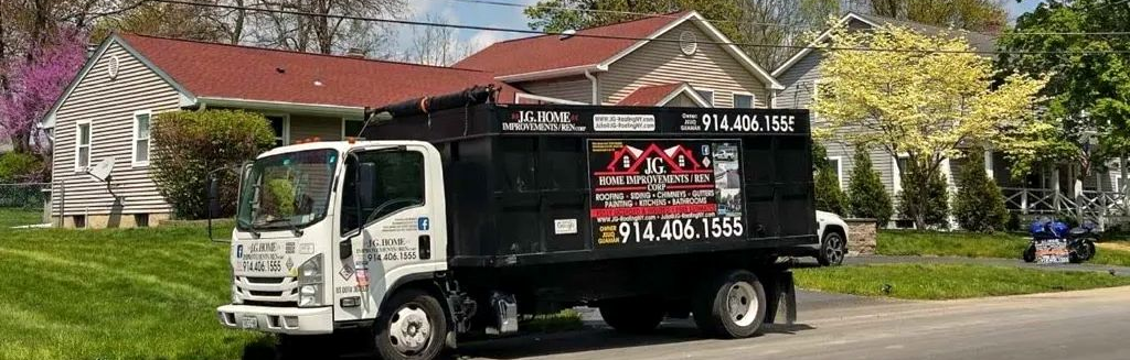 White dump truck parked on a street in front of a house, with a lawnmower in the background.