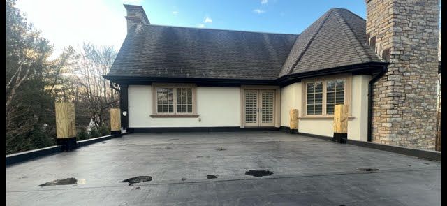 A large white house with a black roof and a large driveway.