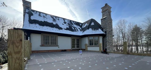 A large house with a stone chimney and a patio in front of it.