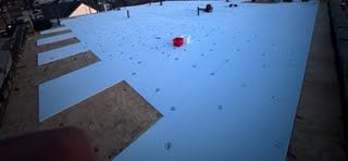 A red balloon is floating in the air on a snowy roof.