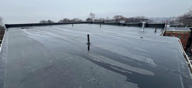 The roof of a building is covered in ice and snow on a cloudy day.