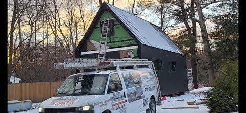 A white van is parked in front of a house under construction.