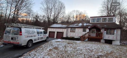 A van is parked in front of a house in the snow.