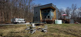 A house with a van parked in front of it and chairs in front of it.