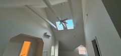 A hallway with a ceiling fan and a skylight in the ceiling.