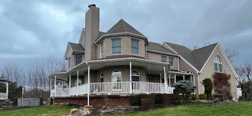 A large house with a large porch on a cloudy day.