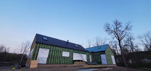 A green house with a black roof is being built.