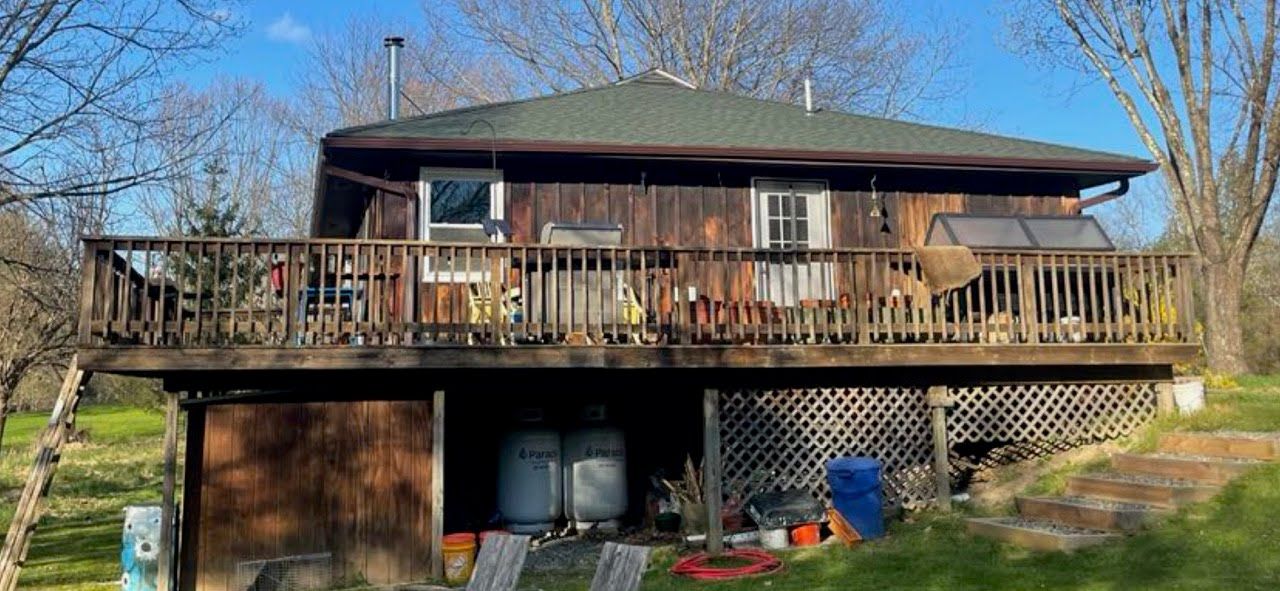 A large wooden house with a large deck in the middle of a field.