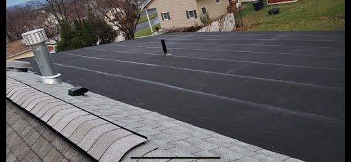 A roof with a chimney on top of it and a house in the background.