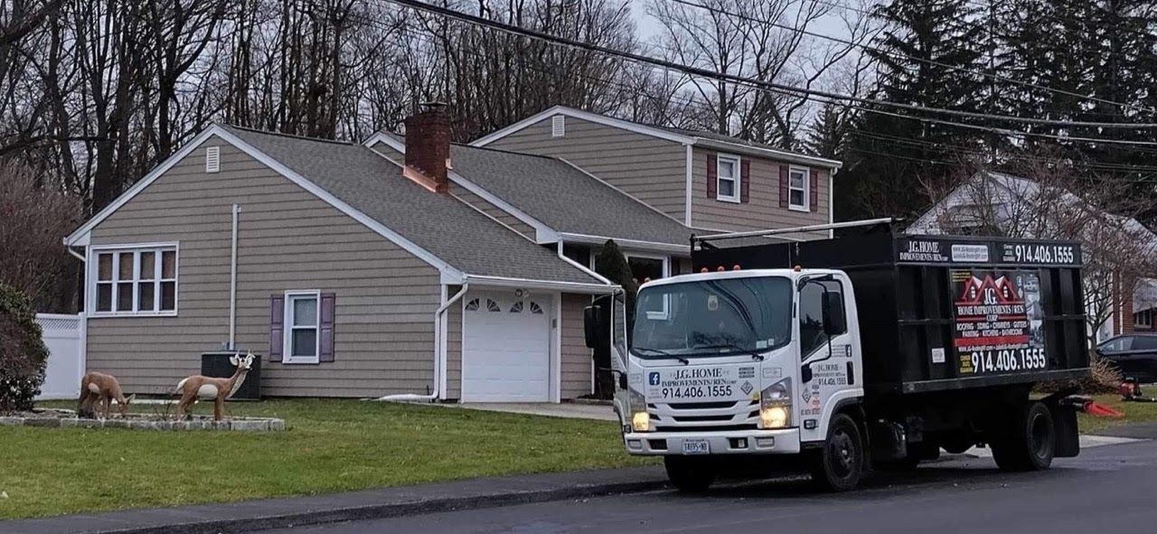 A dumpster truck is parked in front of a house.